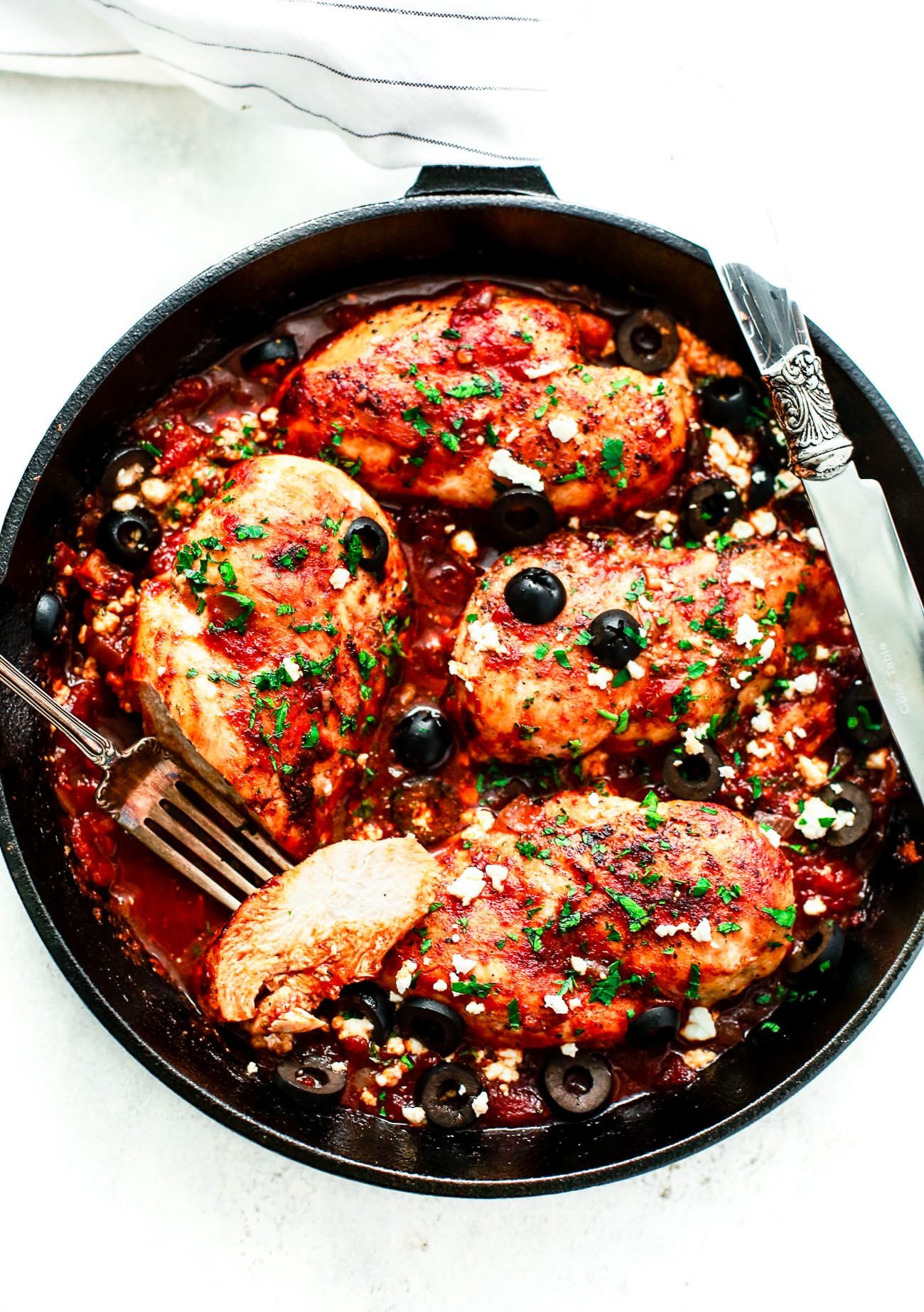 overhead view of a cast iron skillet containing Mediterranean Chicken breast