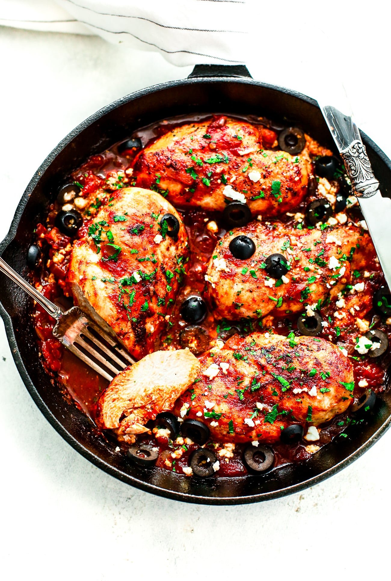 overhead view of a cast iron skillet containing Mediterranean Chicken breast