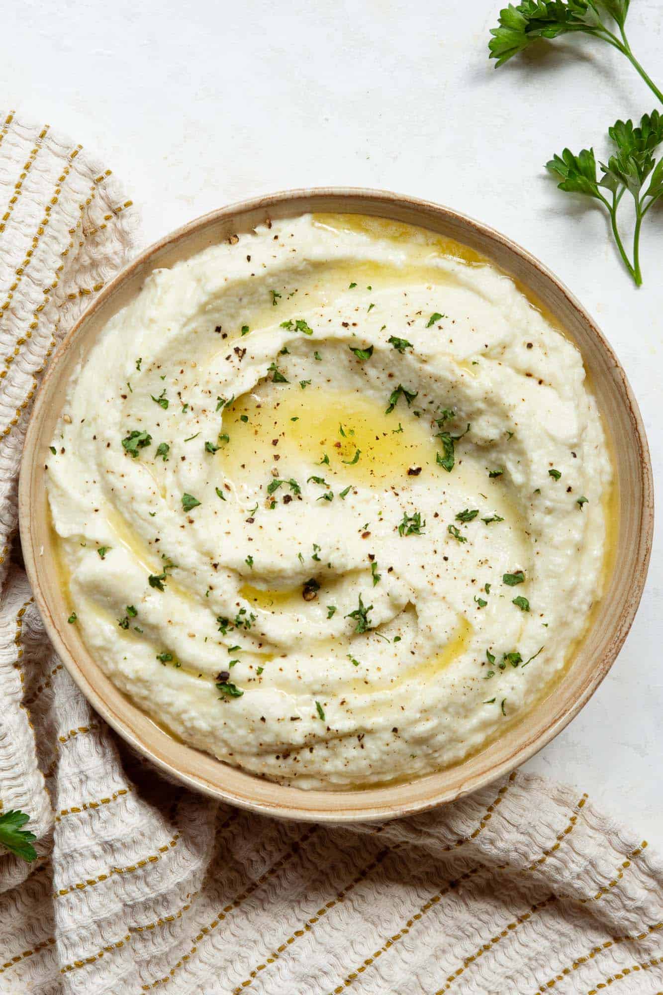 A bowl of mashed cauliflower on a marble countertop.