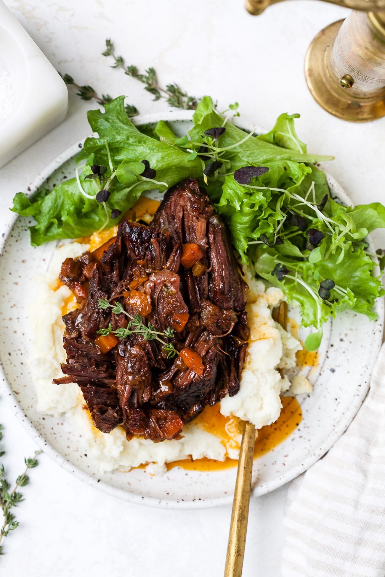 Red wine braised short ribs on a plate with mashed potatoes and salad. 