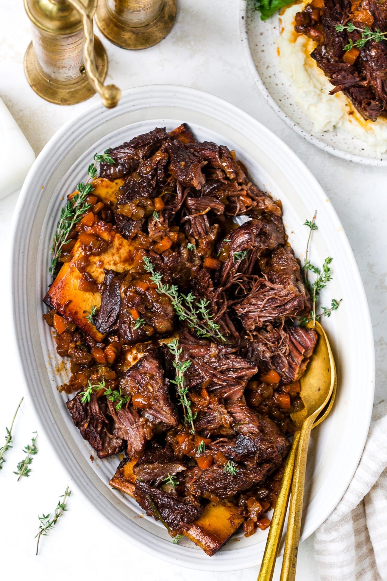 Red wine braised short ribs on a platter with herbs. 