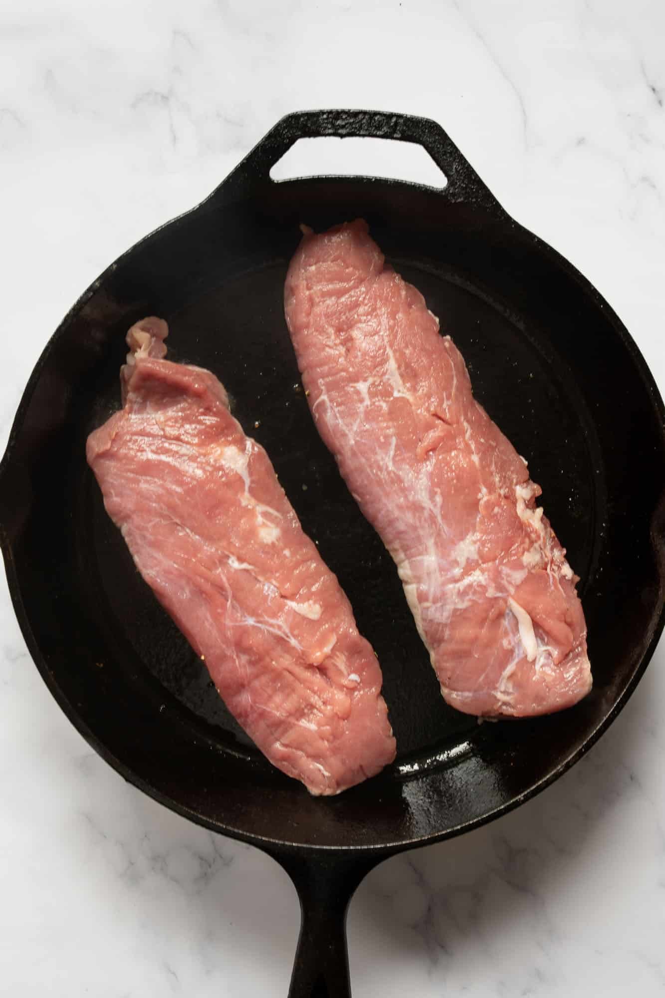 raw pork tenderloin in a cast iron 