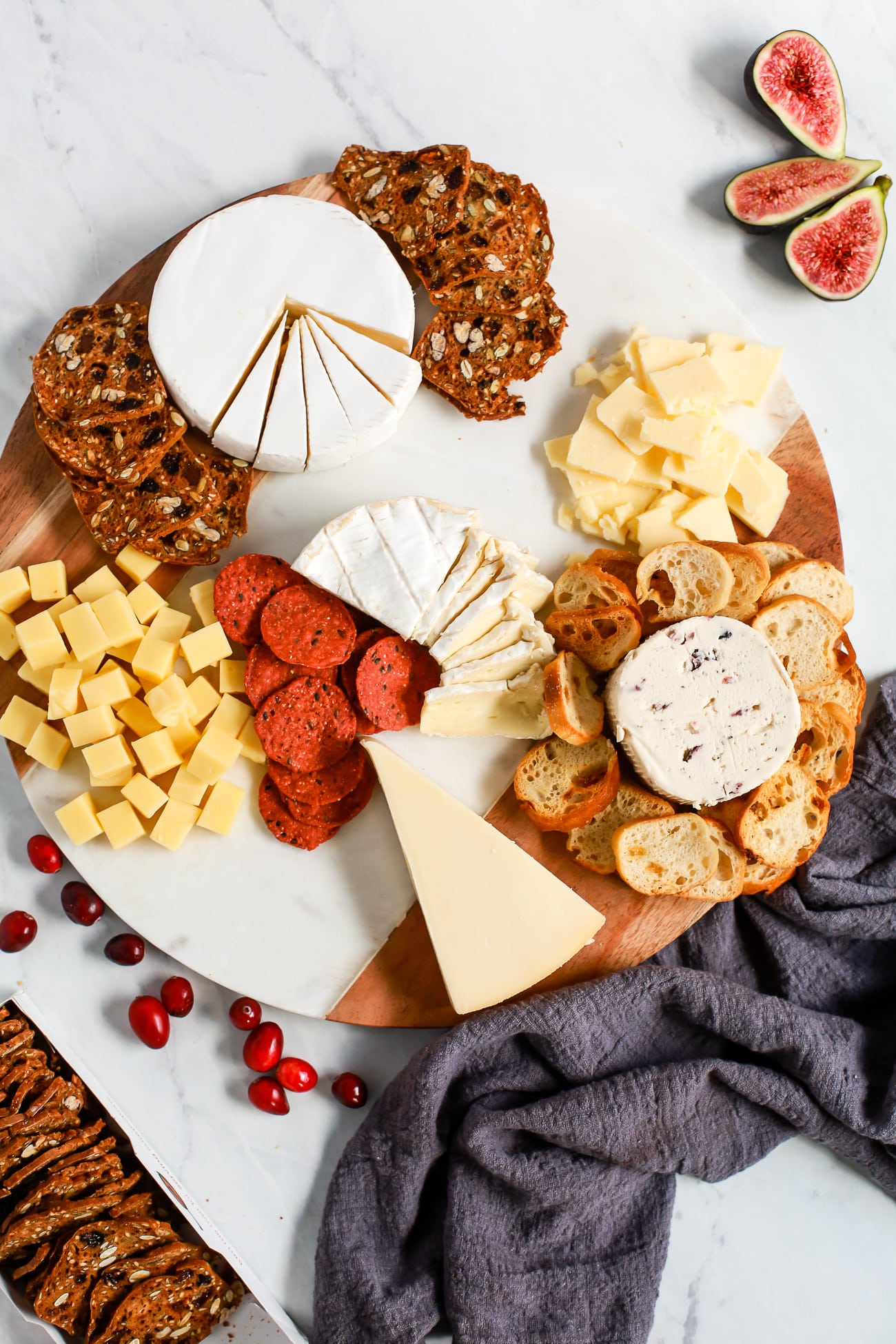 arranging a cheese platter with meat, cheese, crackers, and fruit