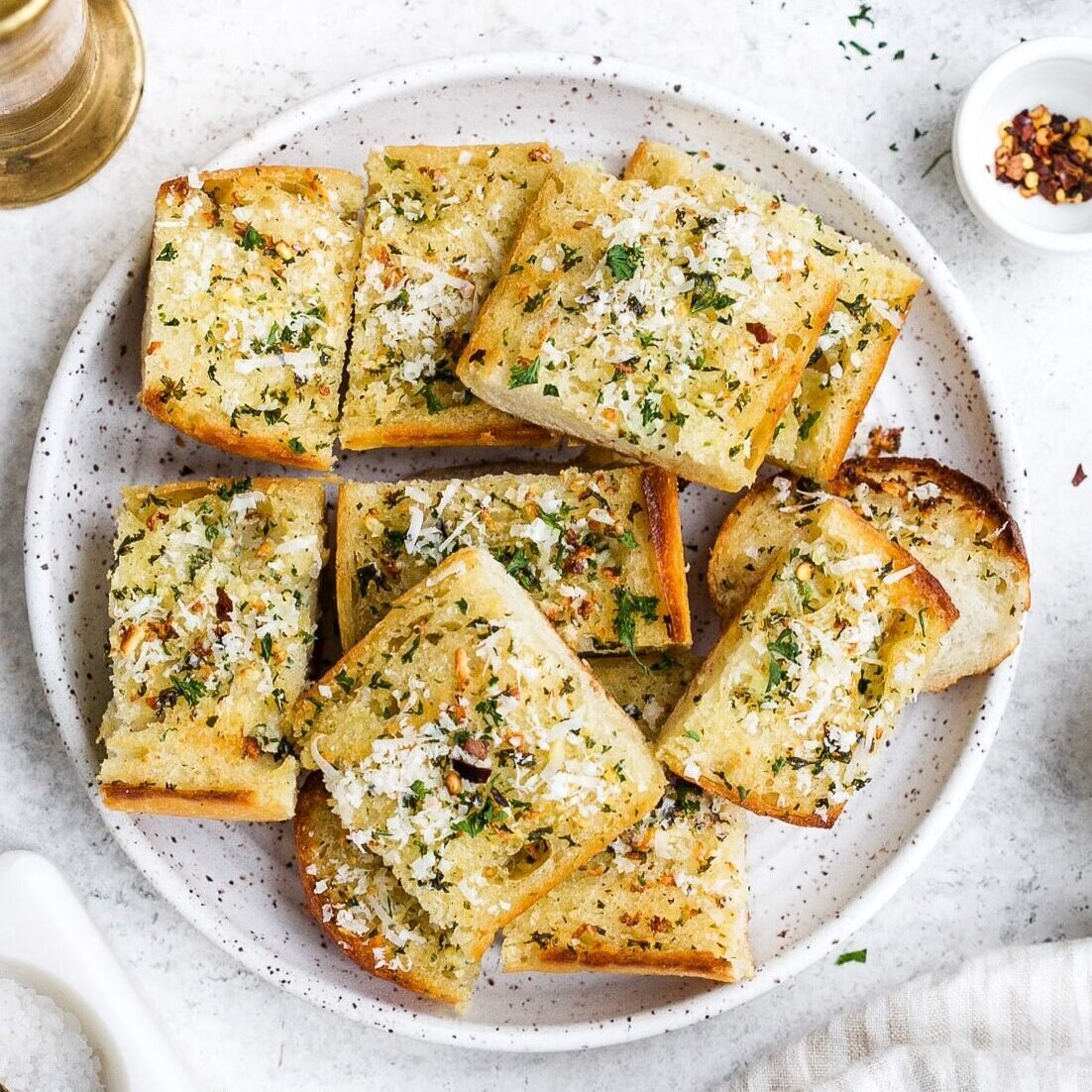Pieces of garlic bread on a white serving plate.