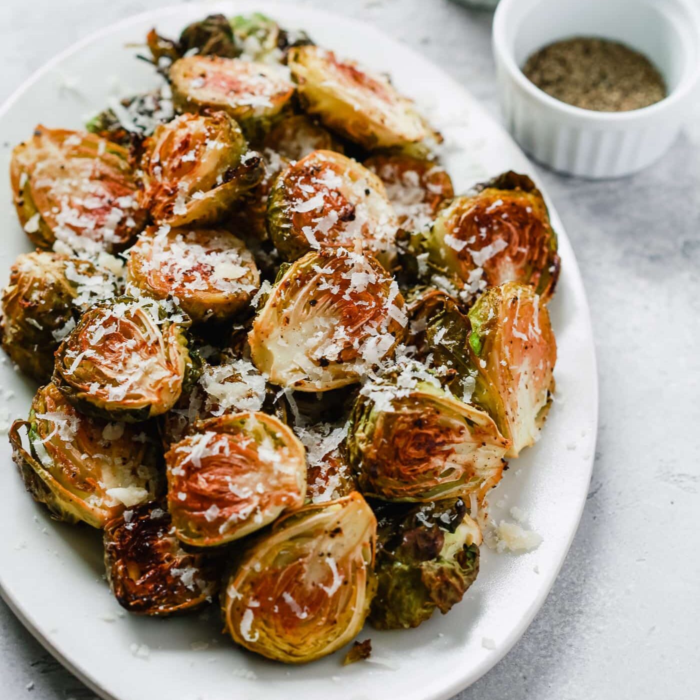 Overhead photo of a white serving platter with garlic parmesan roast brussels sprouts.