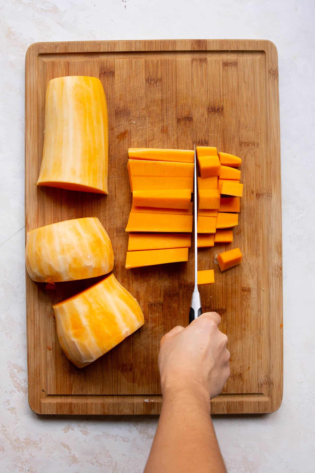 Lay the squash half on its flat side, and cut into three parts. The half ring portions will be harder to cut very evenly.