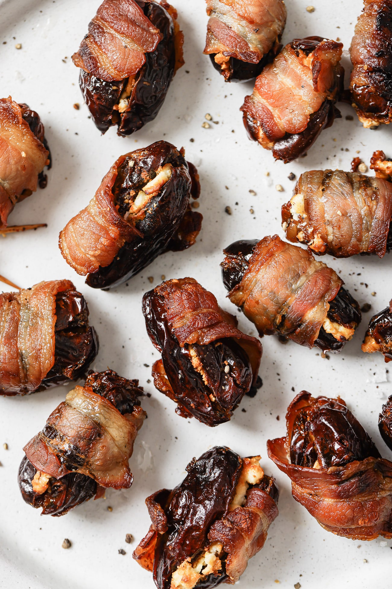 Close up of bacon-wrapped dates on a white plate. 