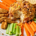 Cheese Ball on a plate with vegetables, crackers, and bread sticks.