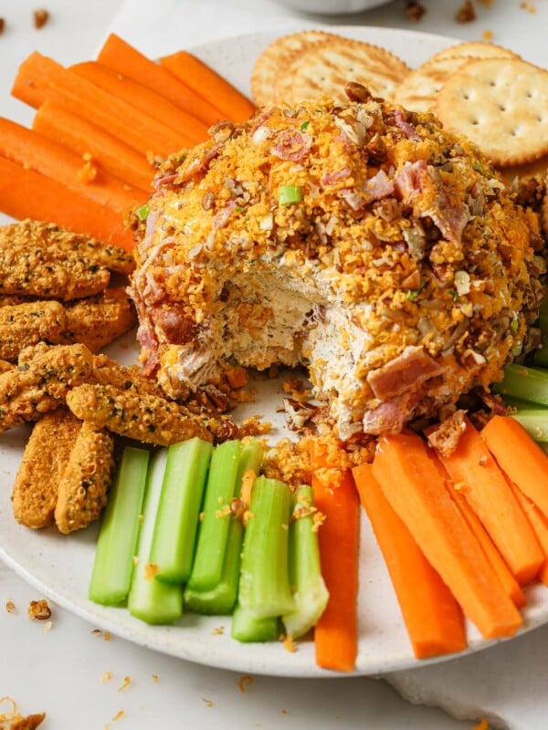 Cheese Ball on a plate with vegetables, crackers, and bread sticks.