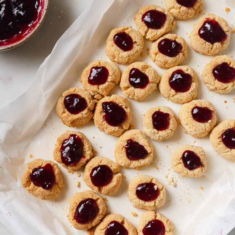 overhead view of Cranberry Thumbprint Cookies on a baking sheet covered with parchment paper.