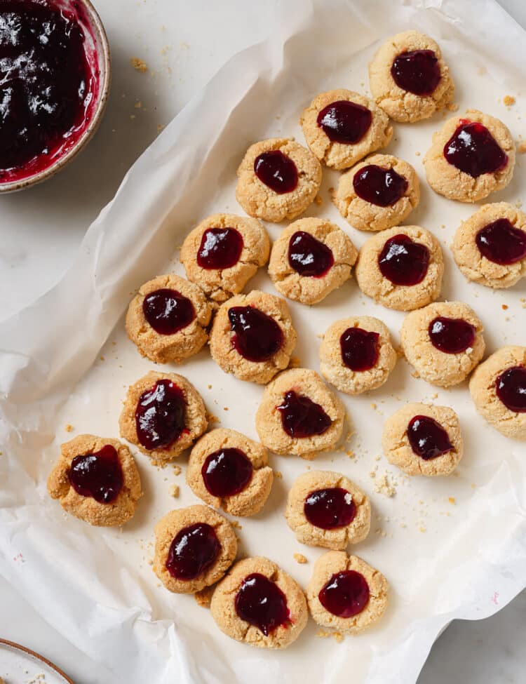 overhead view of Cranberry Thumbprint Cookies on a baking sheet covered with parchment paper.