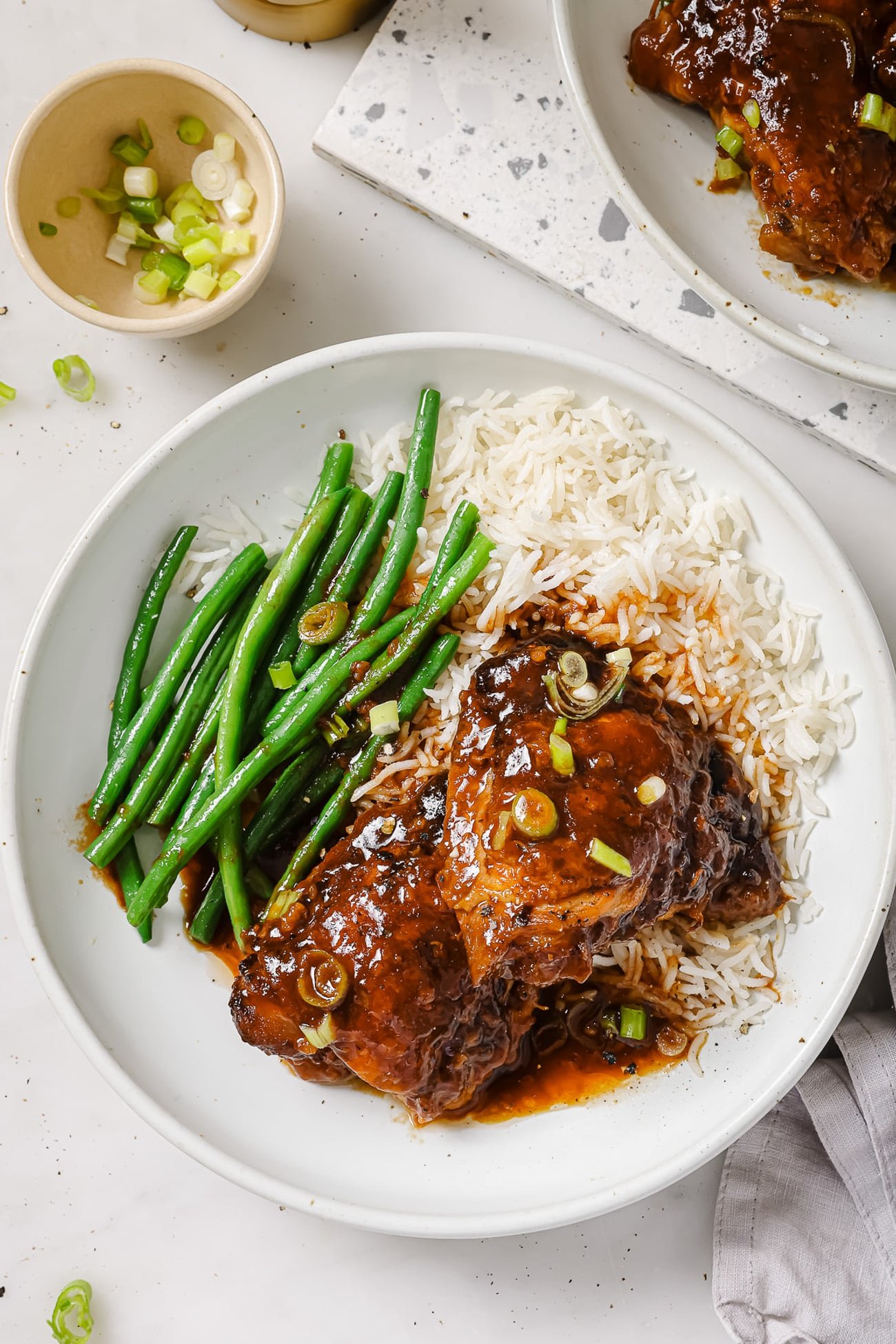 Slow Cooker chicken thighs on a white plate with green beans and rice.