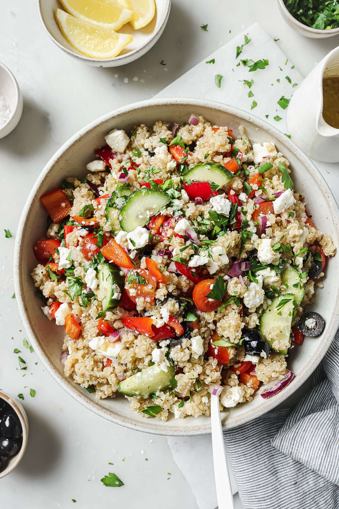 Close up of Greek quinoa salad in a white bowl.
