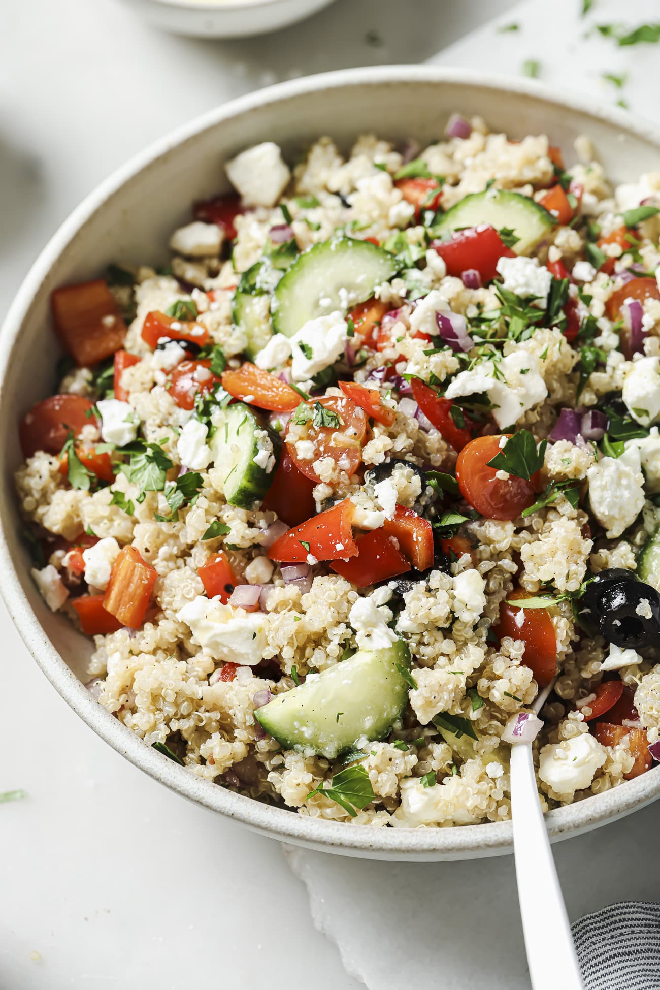 Close up of Greek quinoa salad in a white bowl.