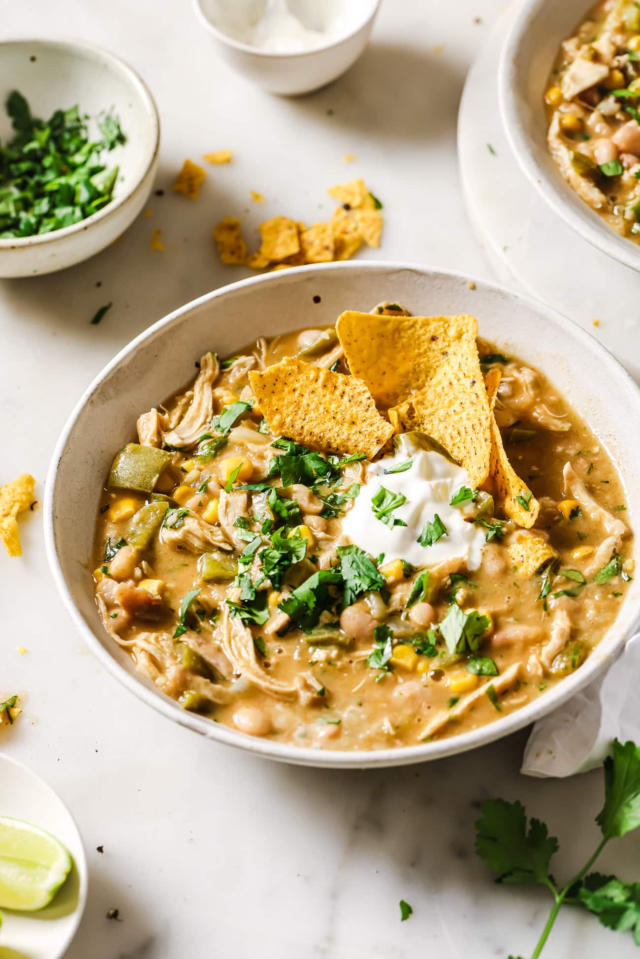 White Chicken Chili in a bowl with toppings and tortilla chips. 