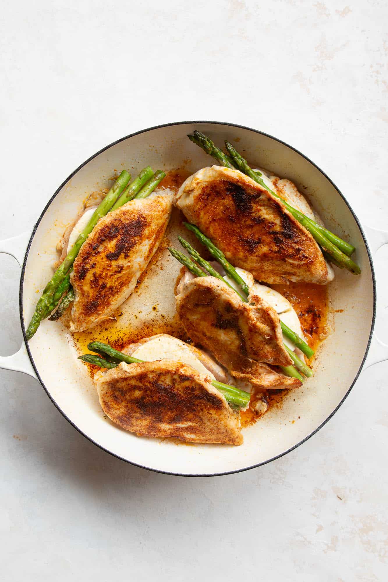 overhead view of a cast iron skillet containing asparagus stuffed chicken breast