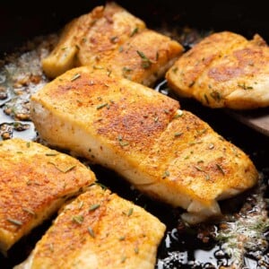 closeup of flaky garlic butter halibut fish in a cast iron skillet