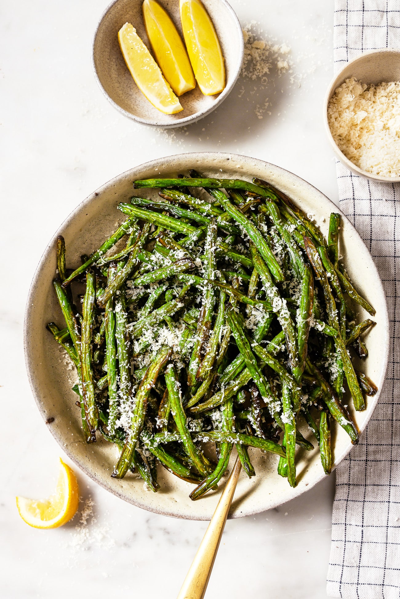 A bowl of air fryer green beans with parmesan cheese on top.