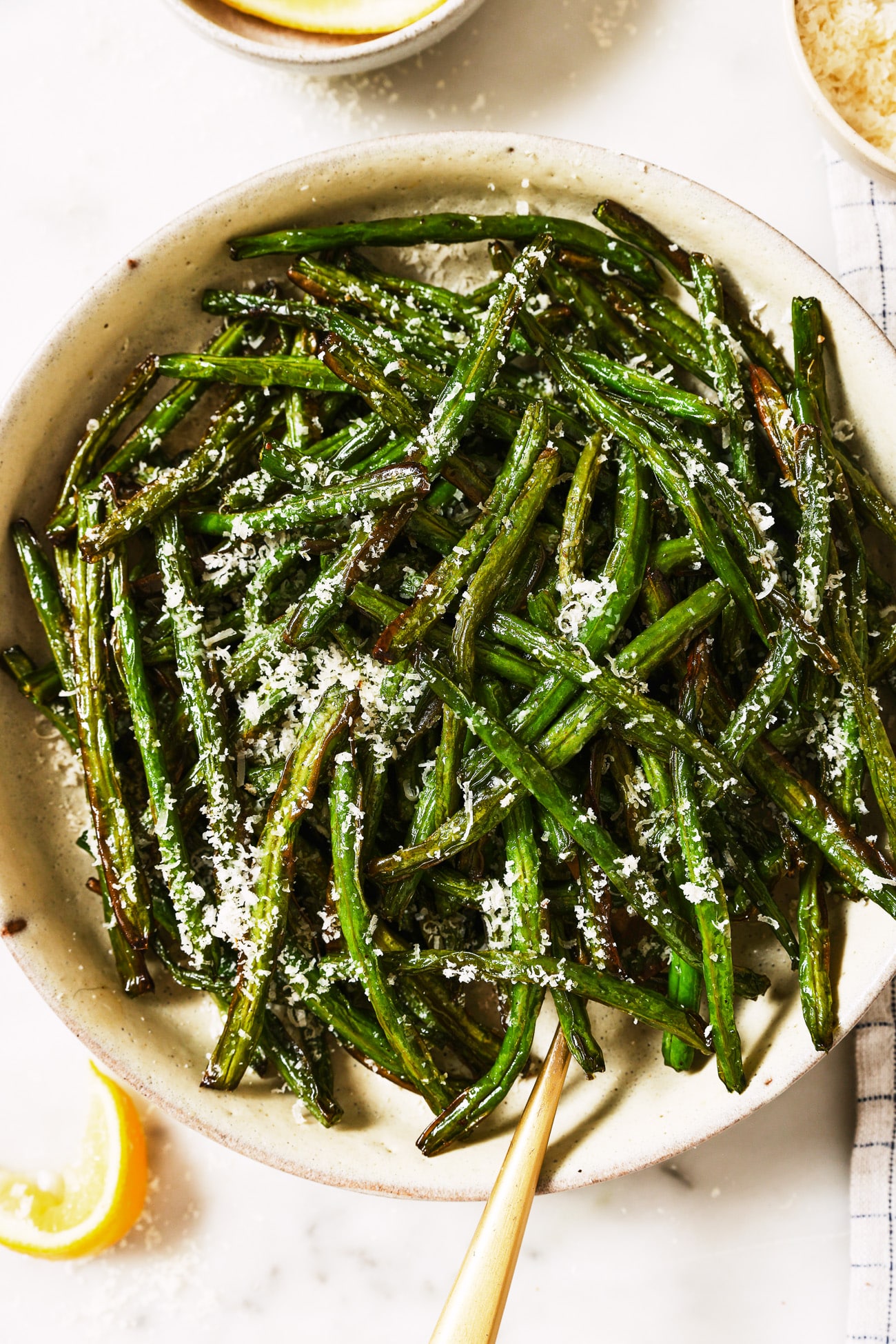 A bowl of air fryer green beans with parmesan cheese on top.