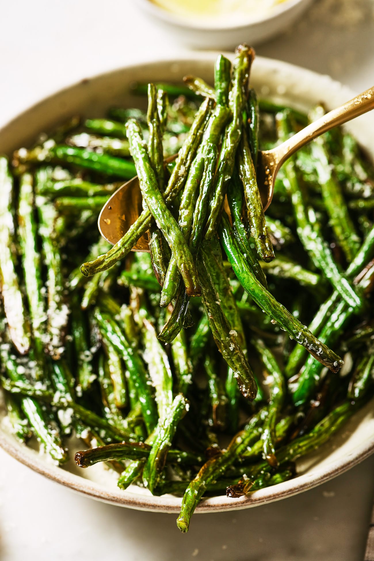 A close up of air fryer green beans with a spoon dishing out a serving.