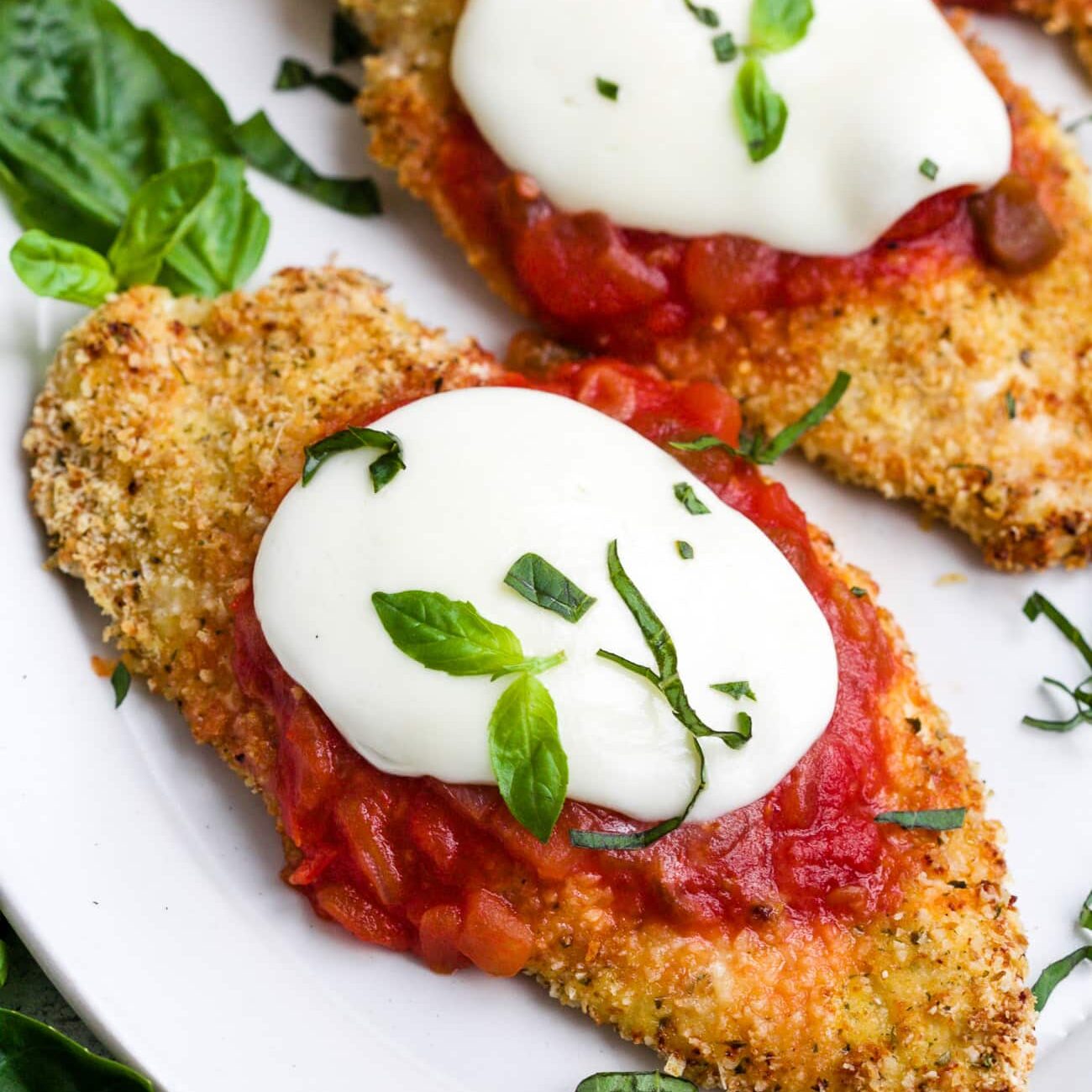 Baked chicken parmesan on a white serving plate.