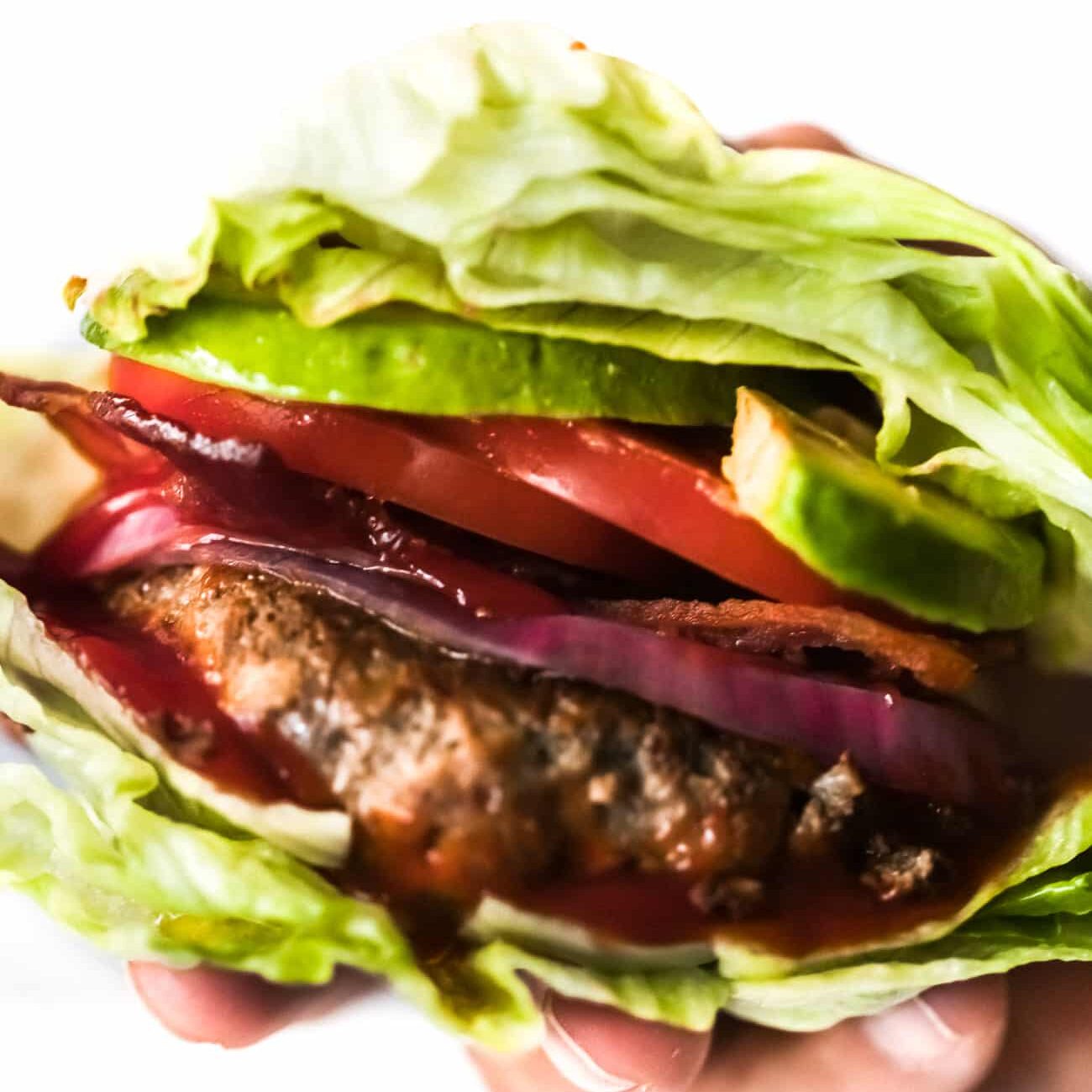 Overhead view of a hand holding a bunless burger.