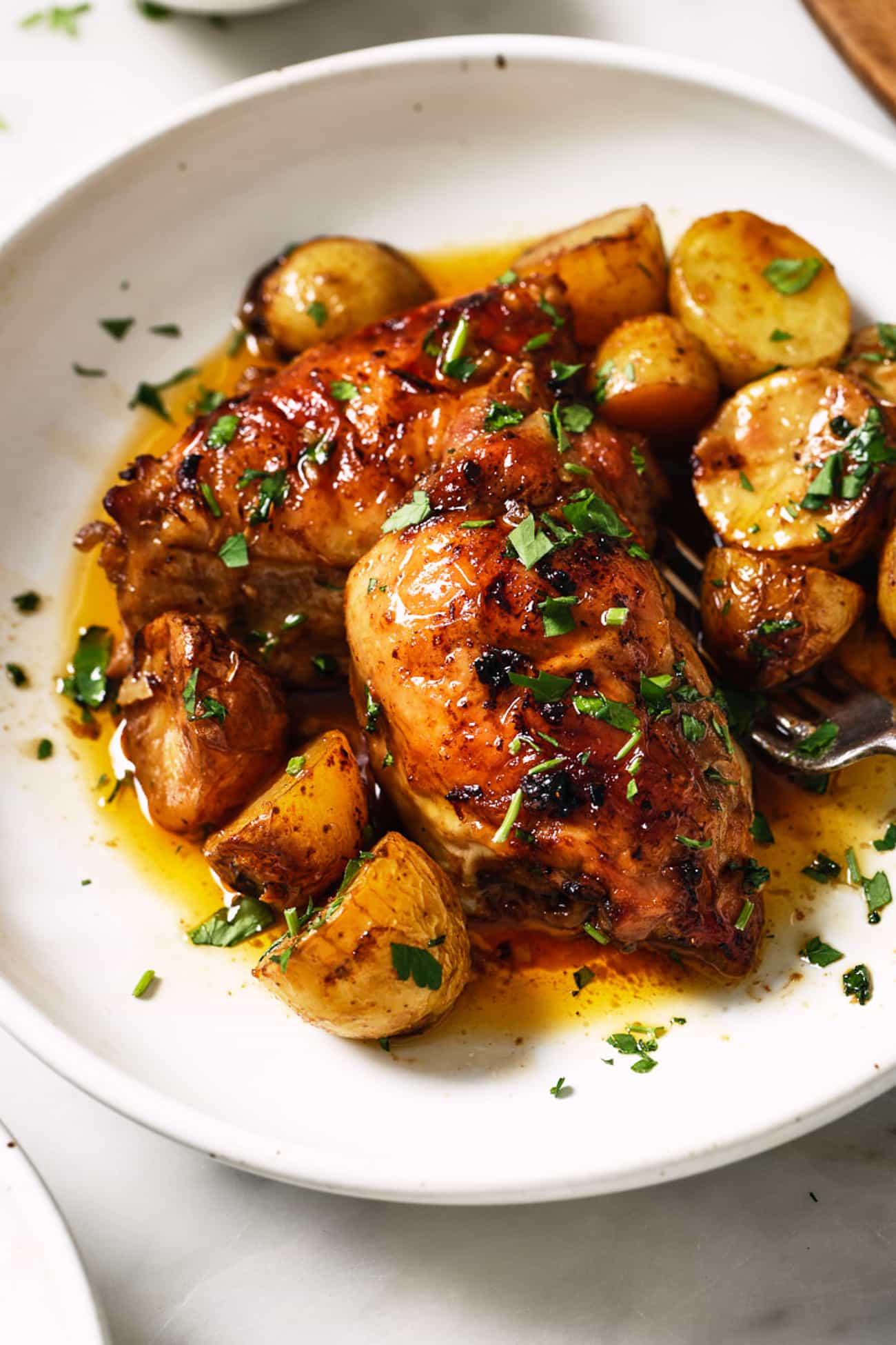 Chicken thighs with sweet potatoes on a white dish. 