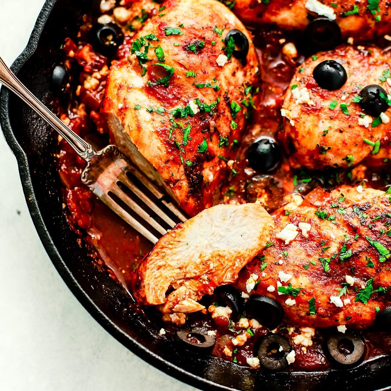 Overhead view of a cast iron skillet containing Mediterranean Chicken breast. One of my favorite date night dinner ideas.