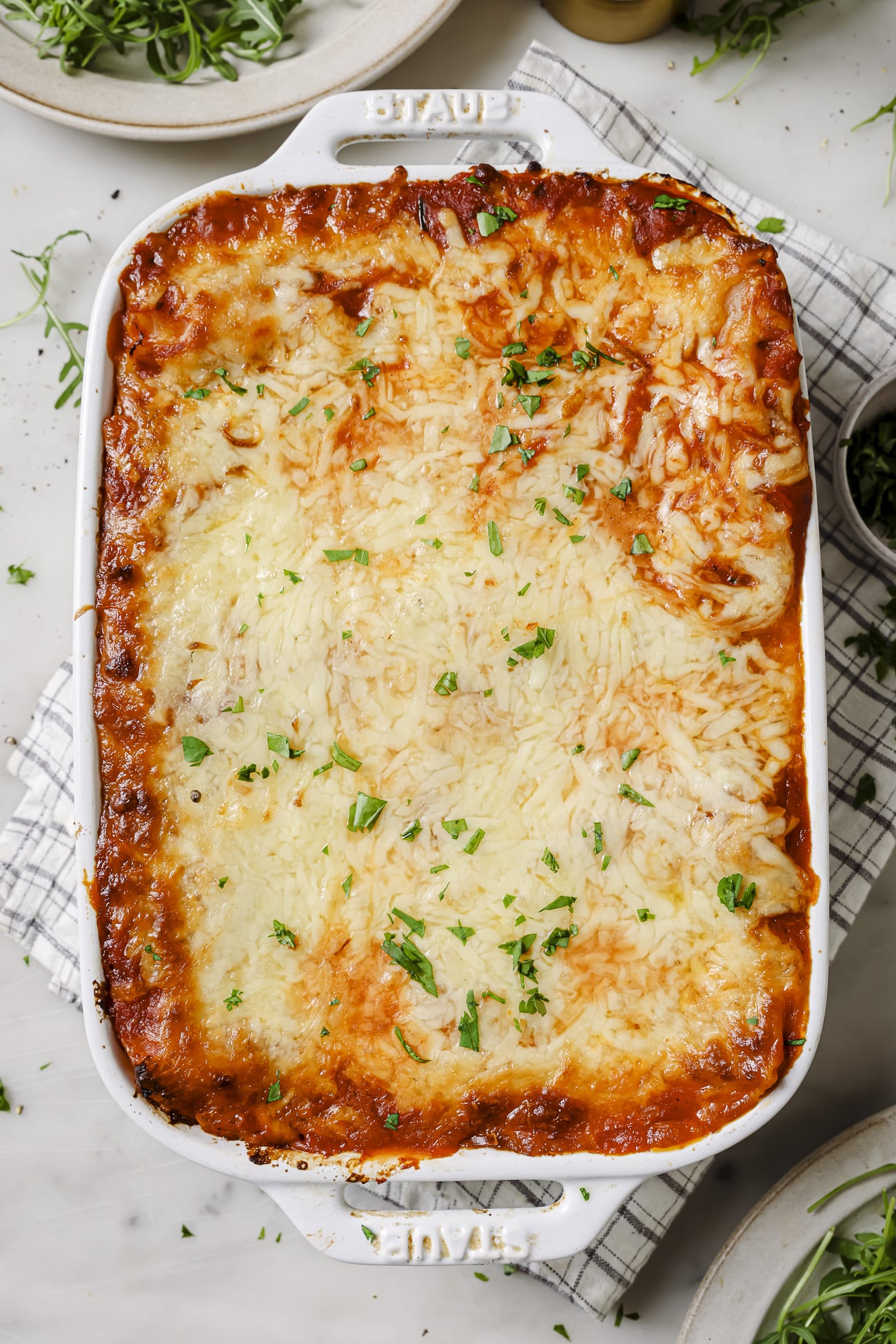 A casserole dish of lasagna rolls with chopped parsley on top. 