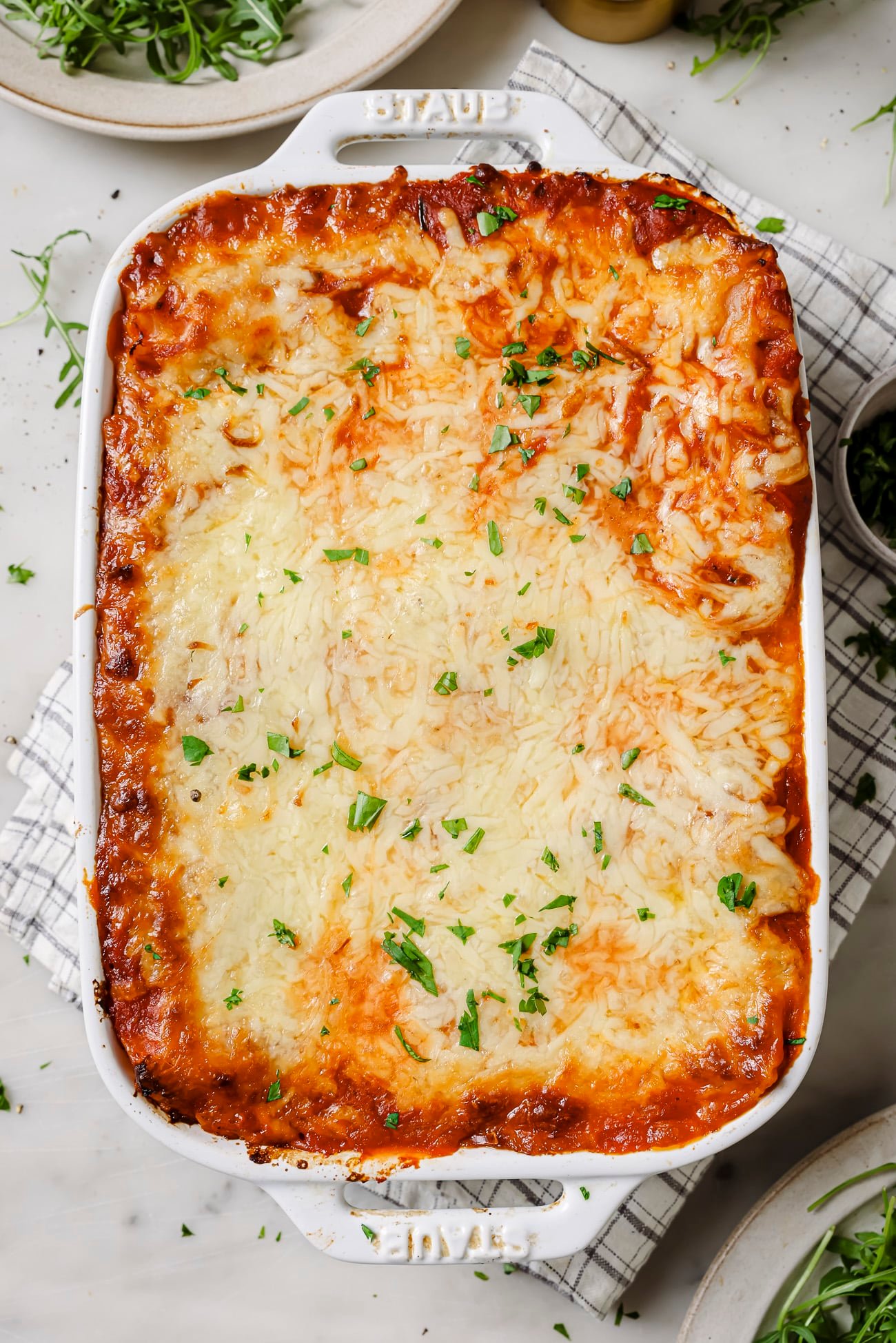 A casserole dish of lasagna rolls with chopped parsley on top. 