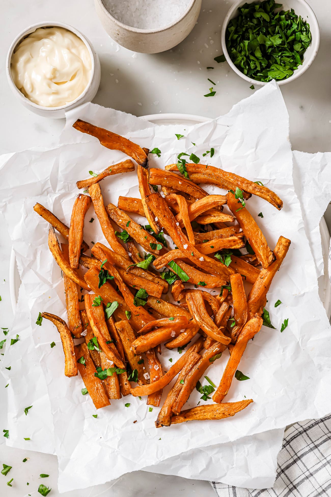 Air fryer sweet potatoes with garnish and dipping sauce on the side. 