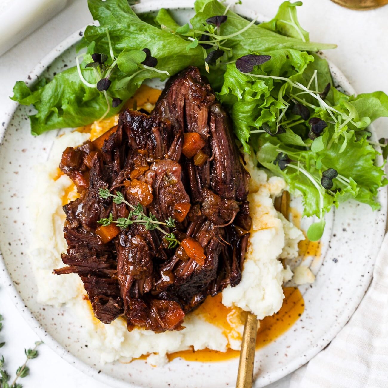 Red wine braised short ribs on a plate with mashed potatoes and a salad. One of my favorite date night dinner ideas.