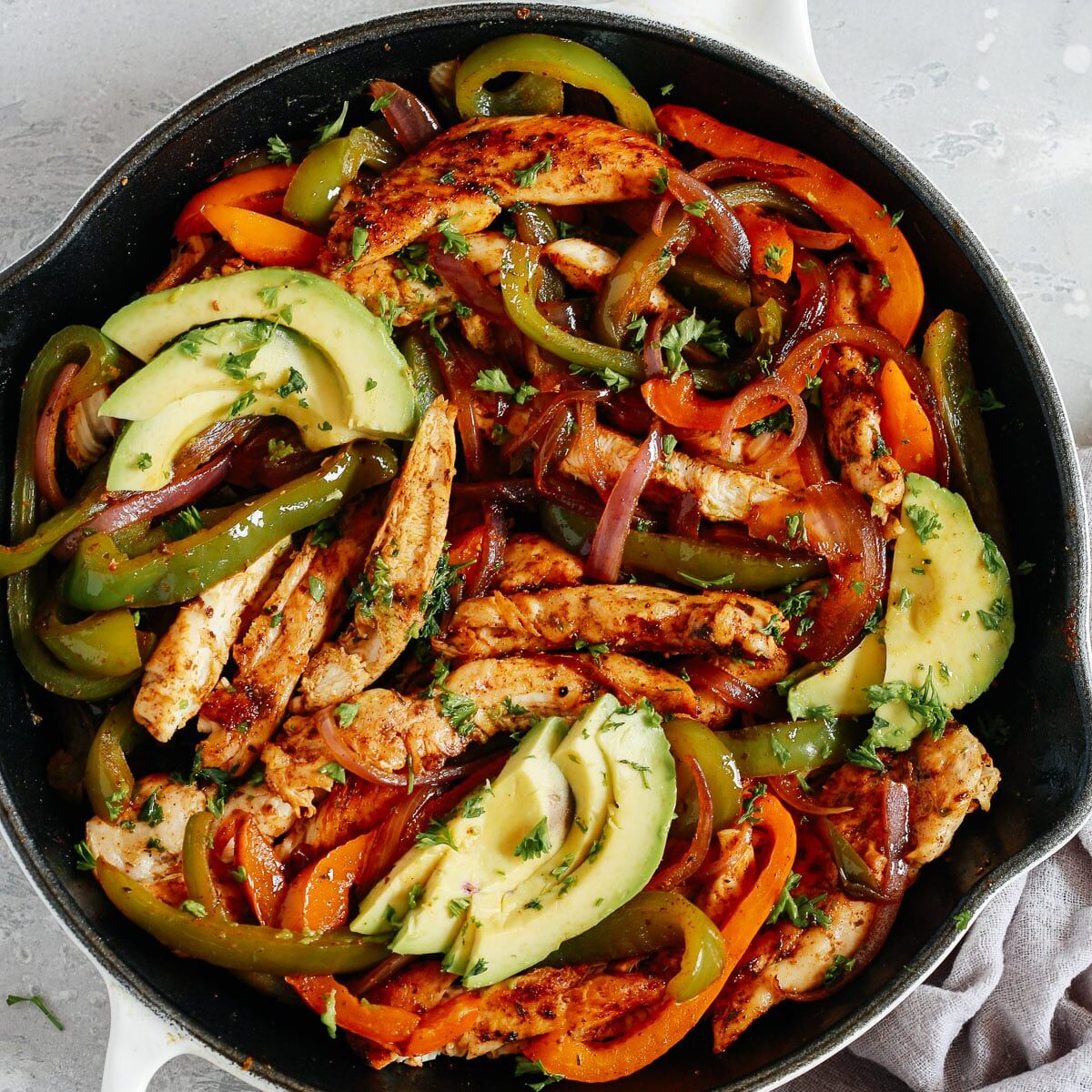 Overhead view of a white skillet containing chicken fajitas. One of my favorite date night dinner ideas.