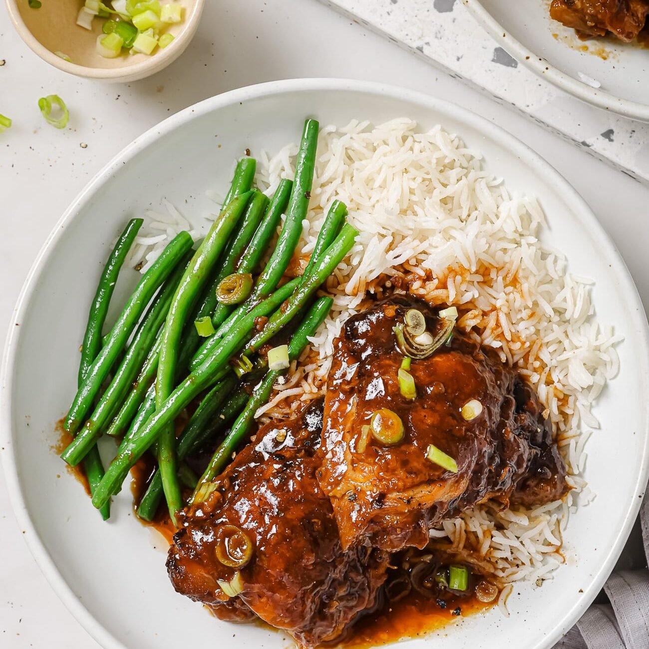 Slow cooker chicken thighs on a plate with rice and green beans. 