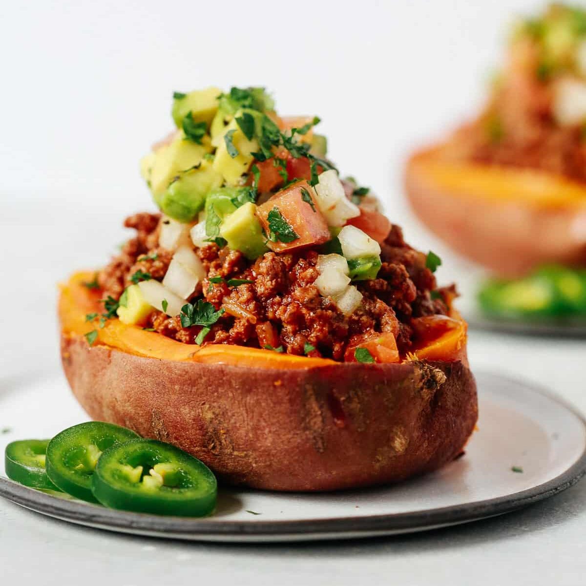 Close-up of a taco-stuffed sweet potato on a white plate. 