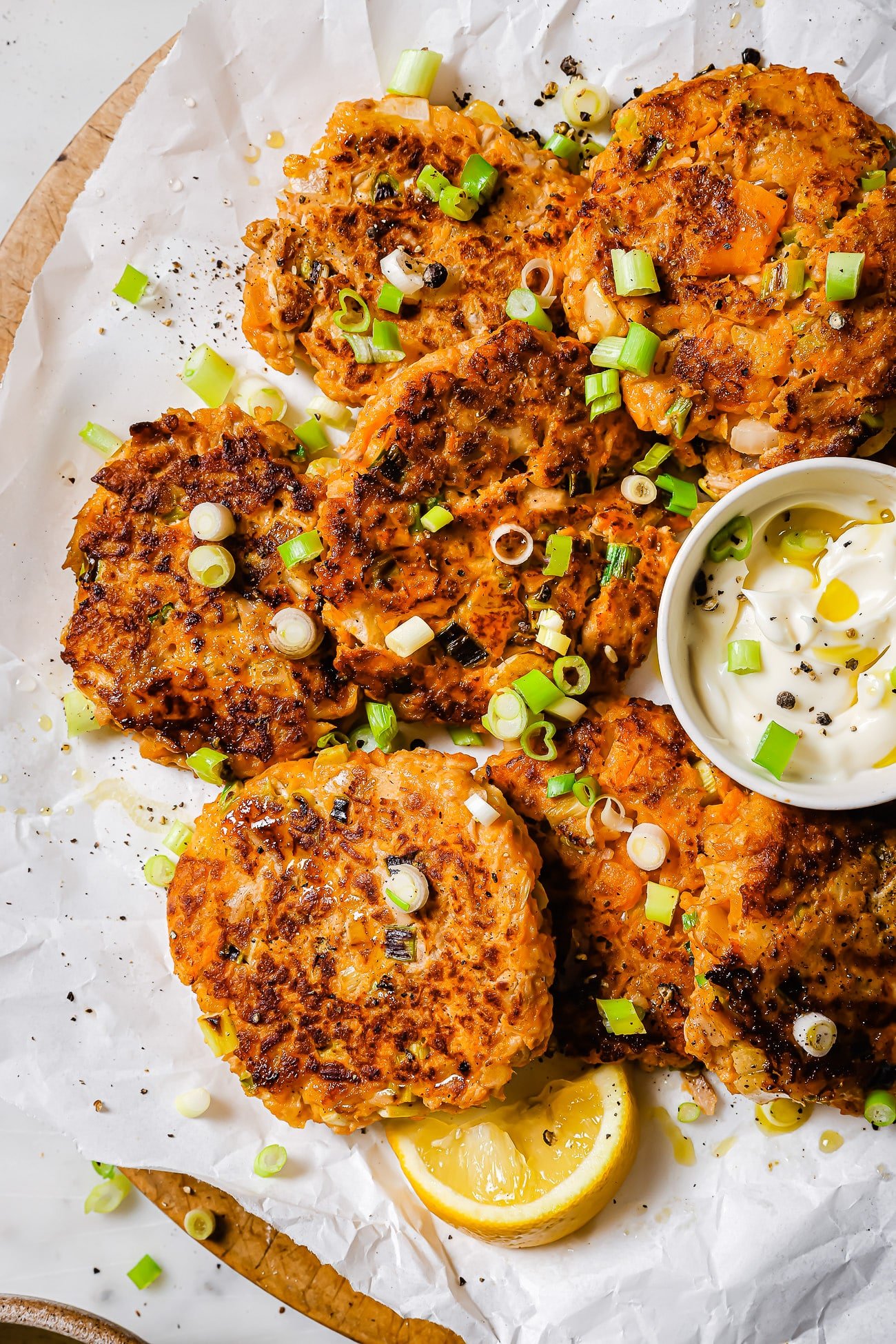 Tuna patties with sweet potato on parchment paper garnished with scallions.