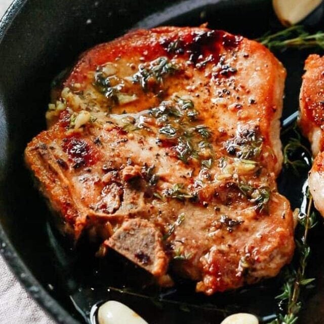 overhead view of a white skillet containing pork chops