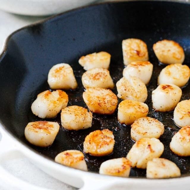 Seared scallops in a pan.