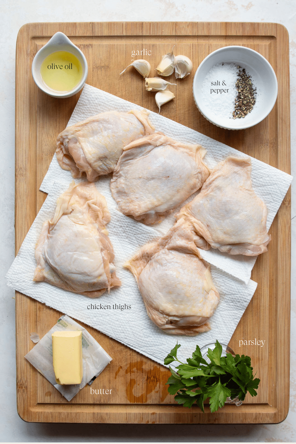 Overhead view of ingredients to make Baked Chicken Thighs on a wooden board. 