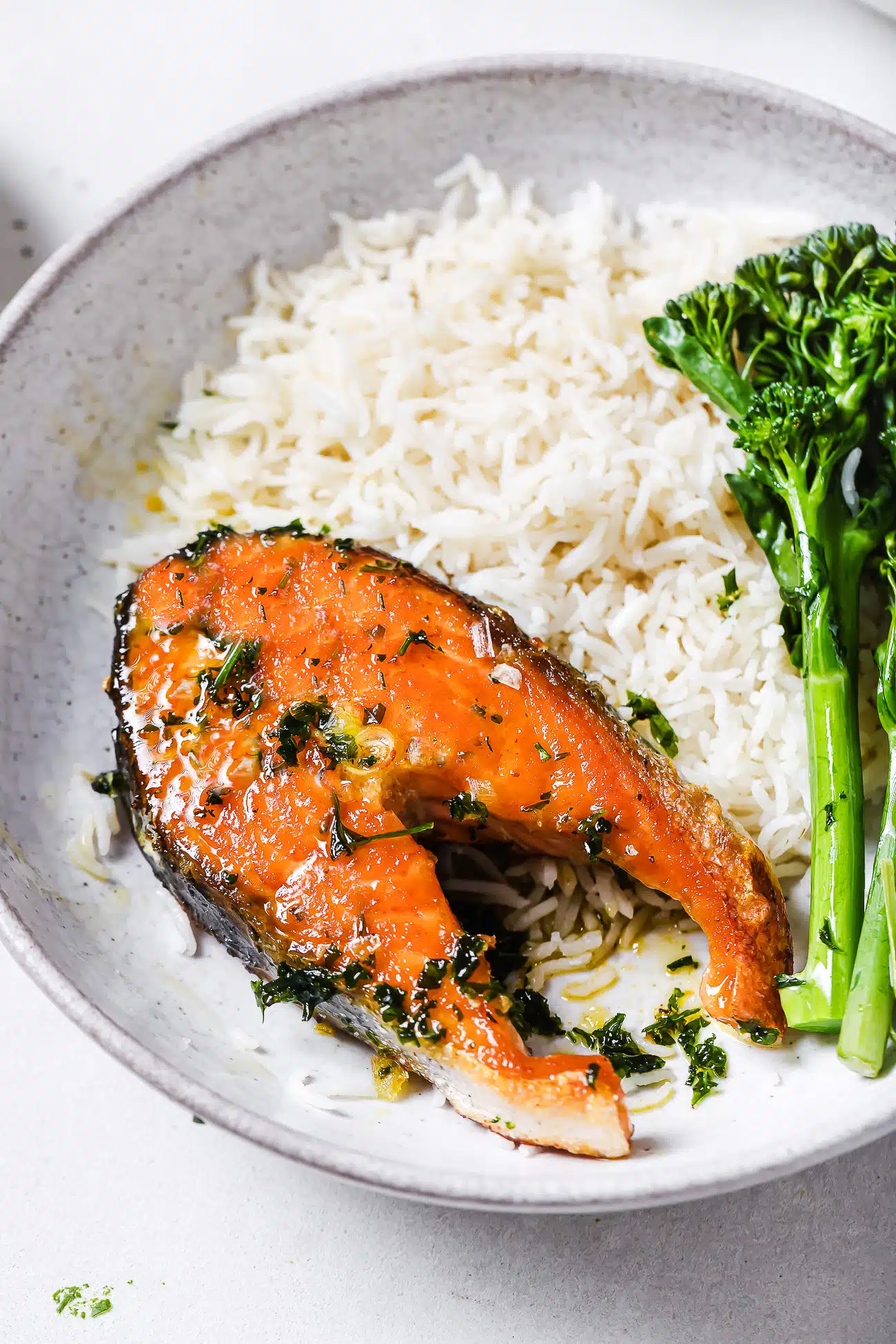 Garlic butter salmon steaks on a plate with rice and green vegetables.