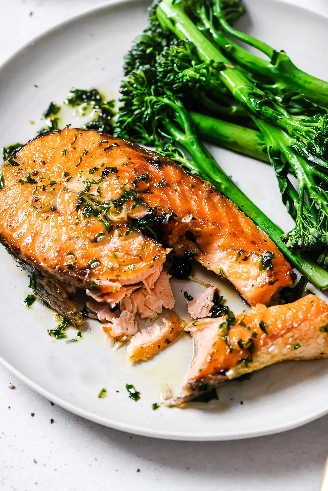 Garlic butter salmon steaks on a plate with green vegetables.