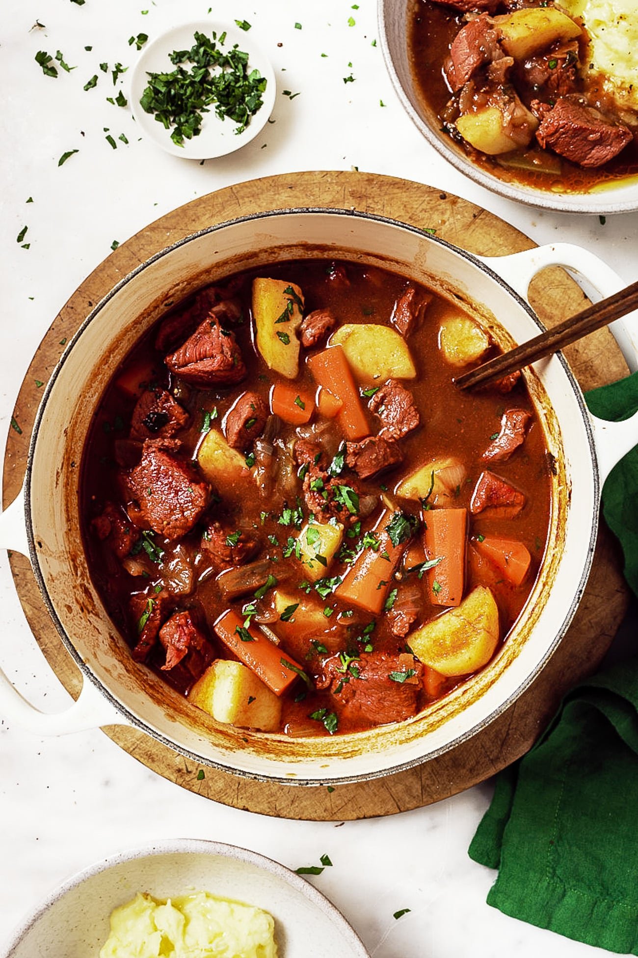 Guinness Beef Stew in a white Dutch oven garnished with parsley. 