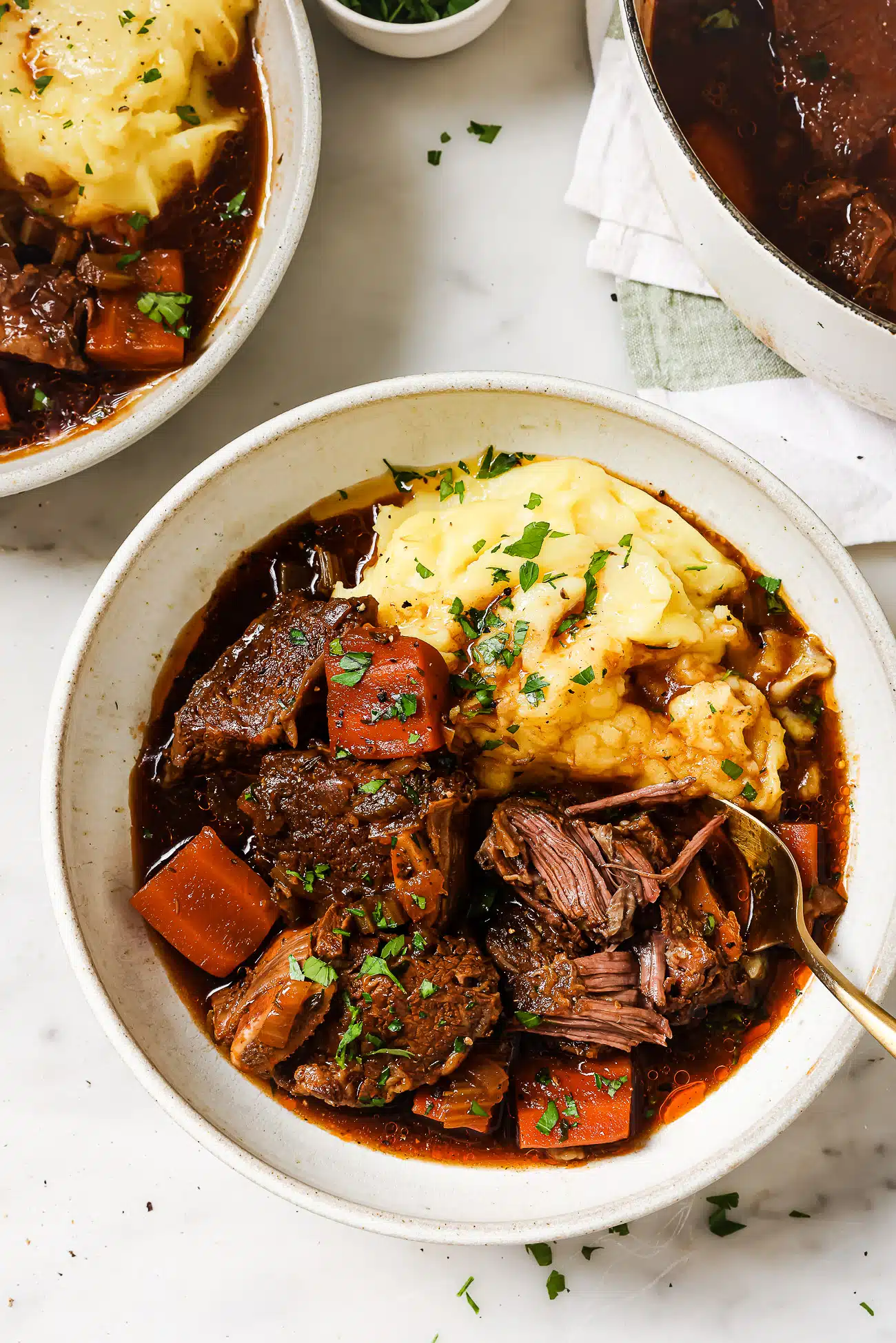 Guinness braised short ribs over mashed potatoes in a white bowl. 