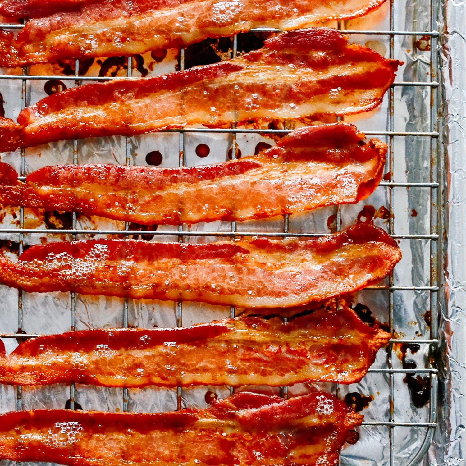 Cooked bacon on a wire rack atop a foil lined baking sheet.