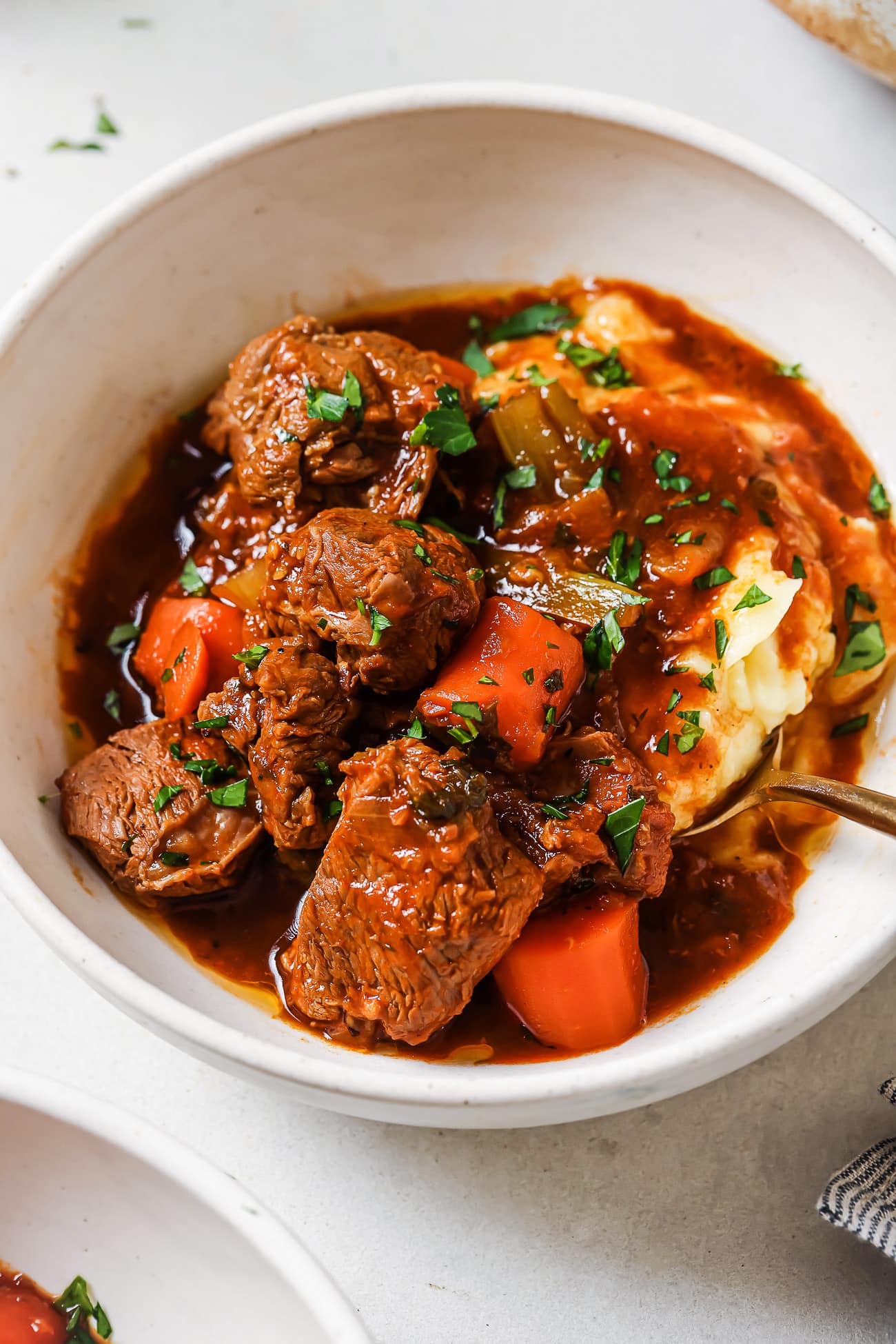 Lamb stew over mashed potatoes in a white bowl.