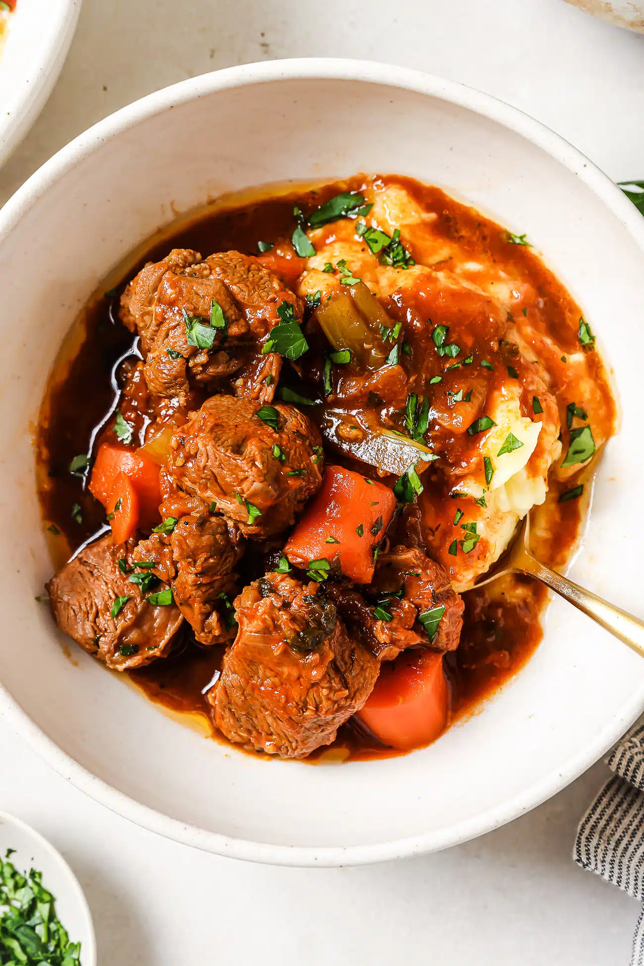 Lamb stew over mashed potatoes in a white bowl. 