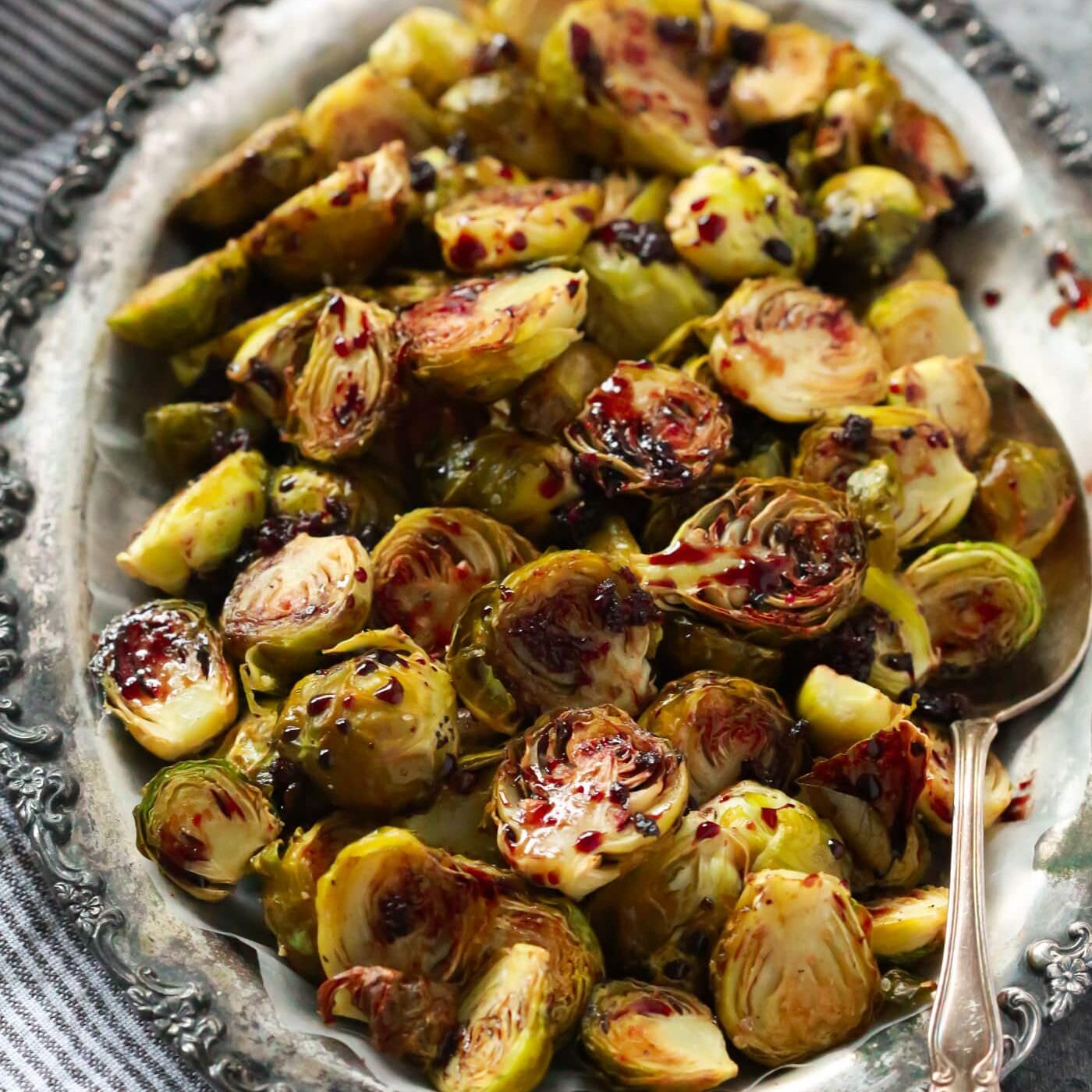 Pomegranate glazed brussels sprouts on a silver serving dish. 