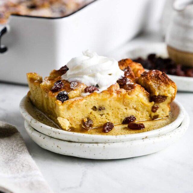 A piece of French toast casserole with whipped topping on a small white plate.