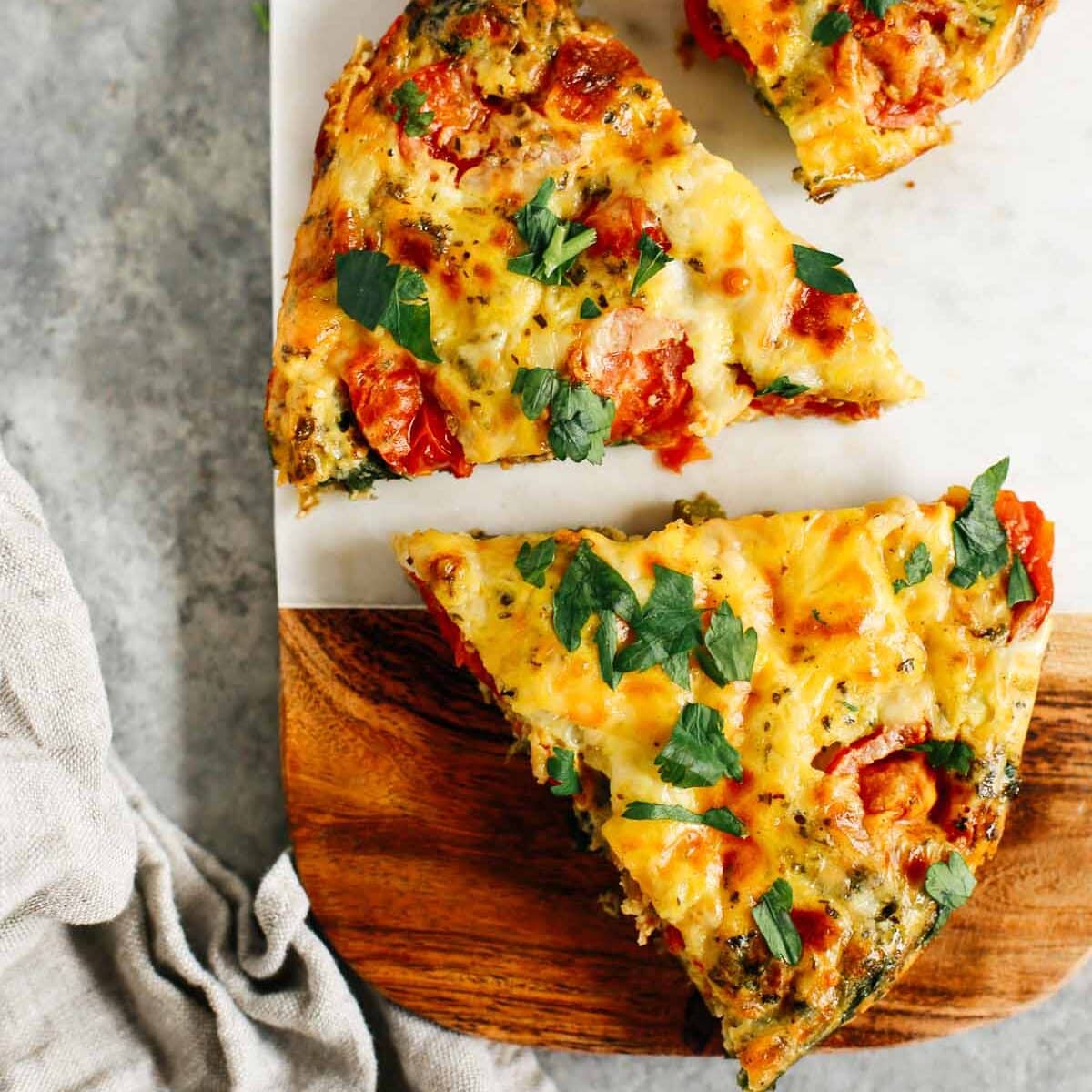 Vegetable frittata cut into pieces on a wooden serving board.