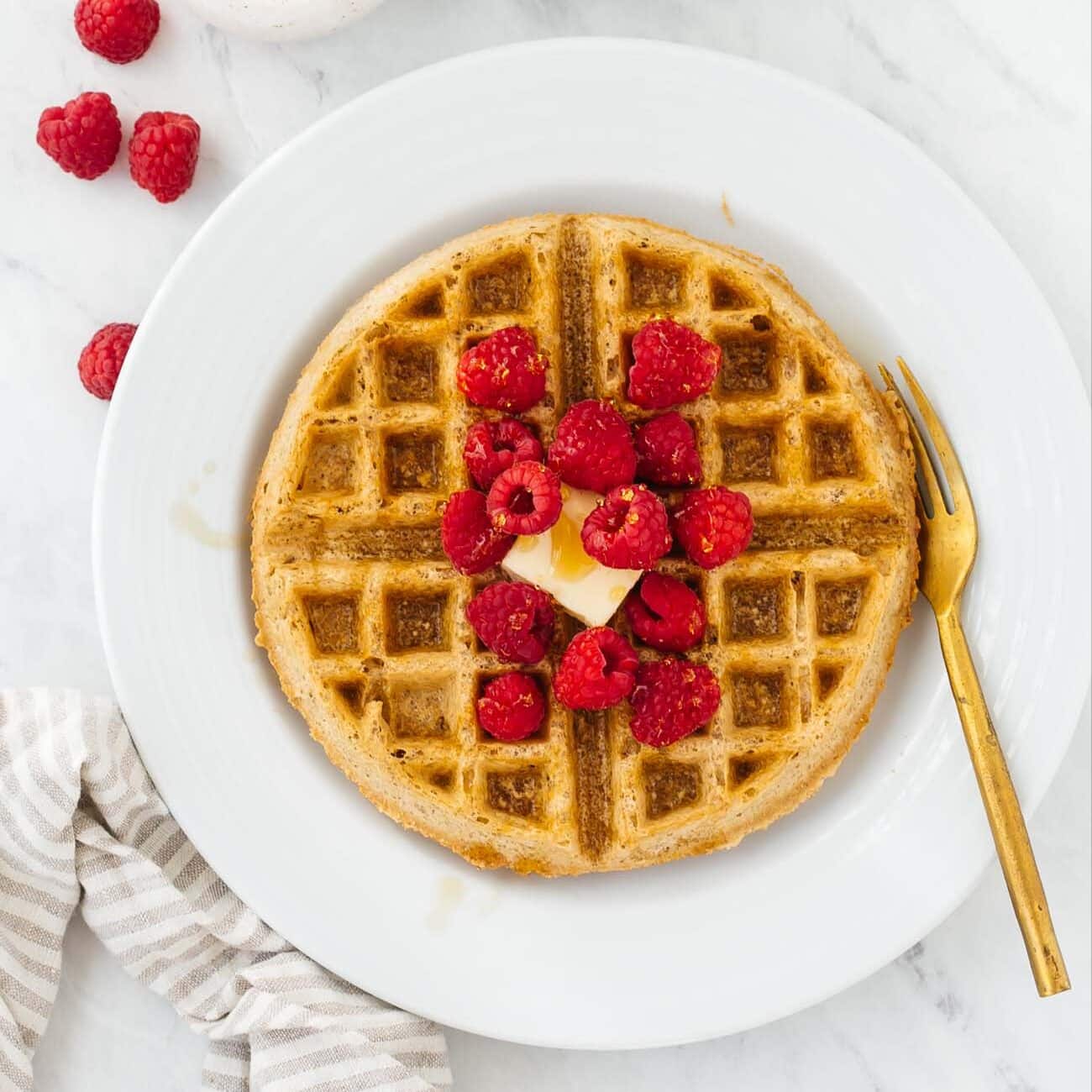 Gluten-free waffles topped with raspberries.